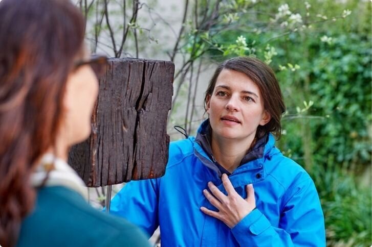 Spezialisierte Pflegefachperson im intensiven Gespräch mit einer jungen Frau draussen