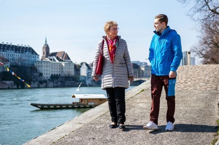 Zivildienstleistender spaziert mit älterer Dame am Rhein 